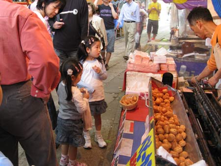 2 japanese girls watching food being prepared